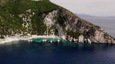 Deniz kıyısı, uçurum ve yeşil tepeleri olan güzel manzaralı bir Yunan adası. Harika bir yaz deniz manzarası. Akdeniz 'de yelkenli tekneler.