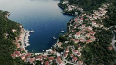 Resimli Yunan adasında hava manzarası, evleri, mavi denizi ve yelkenli tekneleri olan kıyı köyü. Akdeniz 'de lüks bir tatil köyü. Sahne Sahili