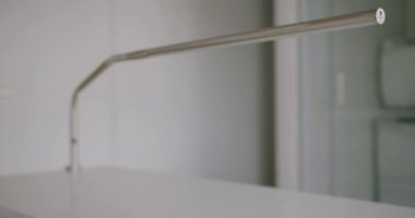 Manikür için beyaz ahşap masaya asılmış minimalist tarzda modern paslanmaz çelik lamba. Detaylar içeride. Çalışma alanı kavramı