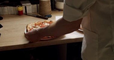 Aşçı adam pizzacı bıçağını restoran mutfağında sıcak İtalyan pizzası için kullanıyor. Müşteri için hazırlanmış pizzayı kesen erkeğin görüntüsü. Yemek pişirme konsepti. Lezzetli fast food