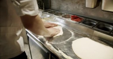 Profesyonel bir aşçı, İtalyan pizzası pişirir ve restoran mutfağında hamur tabanı hazırlar. Pizza yapma süreci. Yiyecek konsepti.