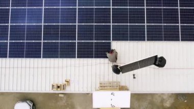 Güneş paneli sistemi kuran erkek işçilerin hava görüntüsü. Alternatif ve yenilenebilir enerji kavramı. Çatıda fotovoltaik güneş modülleri taşıyan erkek teknisyenler 