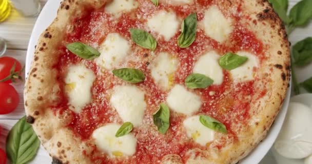 在餐馆里 人们可以在旋转的盘子上看到带有番茄酱 莫扎拉奶酪和新鲜罗勒的马格里塔披萨 将配制的传统人造奶油和配料包起来放在桌上 — 图库视频影像