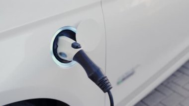 Dışarıdaki elektrik santralinin pilini şarj etmek için prize bağlı olan elektrik makinesine yakın çekim. Elektrikli araba şarjı için güç kaynağı. Çevre taşımacılığı kavramı