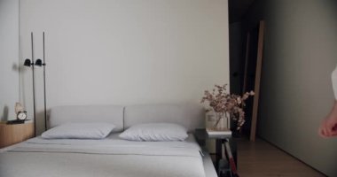 Minimalist bir dairede yatak odası, beyaz tonlarda, modern büyük resim ve siyah lamba ile. Rahat minimalist iç mekan. Şık ev, otel odası, modern mobilya, modern ev tasarımı.