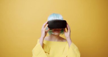 Genç bir kadın oyun oynamak için yenilikçi teknoloji VR gözlükleri kullanıyor ve sanal gerçekliğin 360 VR kulaklığını kullanarak rahatlıyor. Gelecek kavramı, yenilik, teknoloji, oyun, yaşam tarzı.