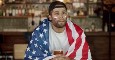 Takımını destekleyen sadık bir futbol taraftarı. Mutlu melez destekçiler kazandıktan sonra seviniyor ve tezahürat yapıyor. Ulusal ABD bayrağı taşıyan bir adam. Bira içmek ve spor maçı izlemek..