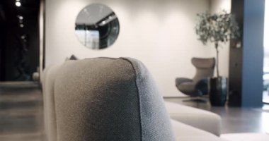 Bej ve beyaz mobilyalı modern Minimalist oturma odası. Köşedeki kanepe, sandalye ve kitaplığı olan lüks modern ev içi. Moda mobilyalar. Minimalist Ev İçi.