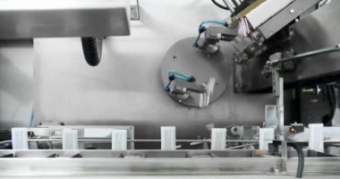 Tıbbi fabrikada üretim hattı. Robotik kol, ilaç paketini taşıma bandına koydu. Otomatik üretim hattında paketlendi. Uyuşturucu ambalajı. İlaç paketleme makinesi.
