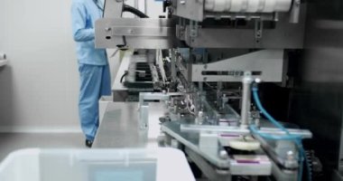 Robot kol, ilaç paketini taşıma bandına koydu. Otomatik üretim hattında paketlenmiş mallar. İlaç paketleme makinesi tıbbi fabrika montaj hattı. İlaç imalatının üretim hattı.