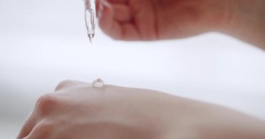 Genç ve güzel bir kadın vücut losyonu sürüyor ve cilt kremi, serum. Kadın elinde pipetle nemlendirici düşürüyor. Doğal güzellik ürünleri. Mineral organik yağ. Kadın serumu uyguluyor.