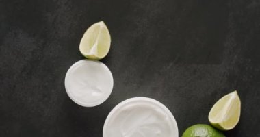 Üst Manzara Beyaz Şişe ve kozmetik için limonlu tüpler stüdyoda siyah bir arka planda dönüyor. Doğal malzemelere dayalı kozmetik yağları, fırça, tonik, vücut bakımı. Farklı kozmetik şişeleri.
