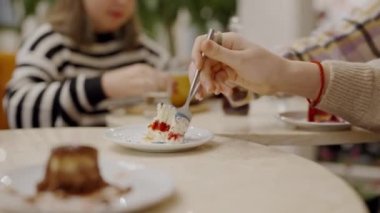 Kafe masasında oturan ve kremalı bisküvi kekinin tadına bakan kadınlar. Bir kadın arkadaşlarıyla yemekten ve kahve molasında kafeteryada tatlı yemekten hoşlanır.