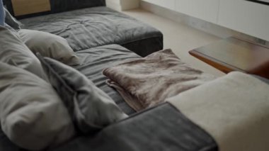 Gri döşemeli rahat bir kanepe, yumuşak yastıklar ve modern iç mimarisi olan rahat oturma odasında katlanmış kadife kumaş. Dekoratif yastıklı kanepe dinlenmek ve evde dinlenmek için.