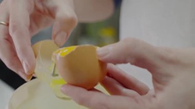 Yumurta kıran ve kafeteryada kek hamuru pişirmek için sarısını beyazdan ayıran kadın ellerine yakın çekim. Kadın şefin tavuk yumurtasından sağlıklı bir kahvaltı hazırladığını gördüm.