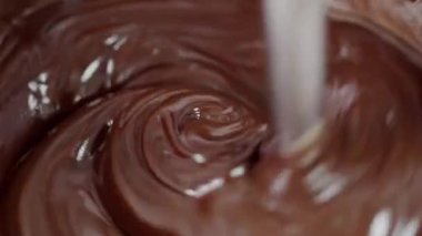 Ev yapımı tatlılar pişiren ve erimiş çikolatayı kaseye karıştıran kişiye yakın çekim. Çikolata hazırlayan çikolatalı şekerlemeler. Tatlıyı pişirme süreci