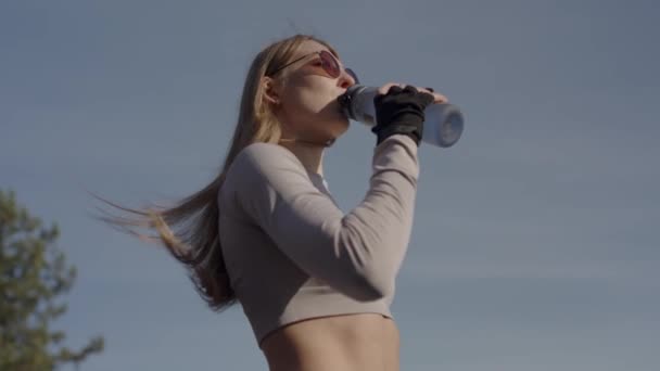 胖女人在室外锻炼后从瓶子里喝水 身穿活动服的年轻女子站在街上 慢跑后休息片刻 神清气爽 健康的生活方式 — 图库视频影像