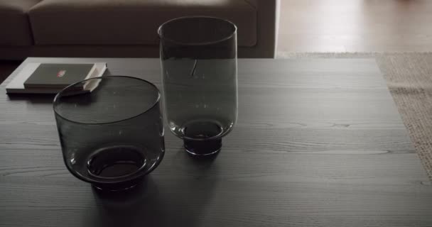 モダンな内装のリビングルームの木製サイドテーブルの空のガラス瓶と本 スタイリッシュなアパートでのインテリアの詳細 ホーム デコレーション要素 — ストック動画