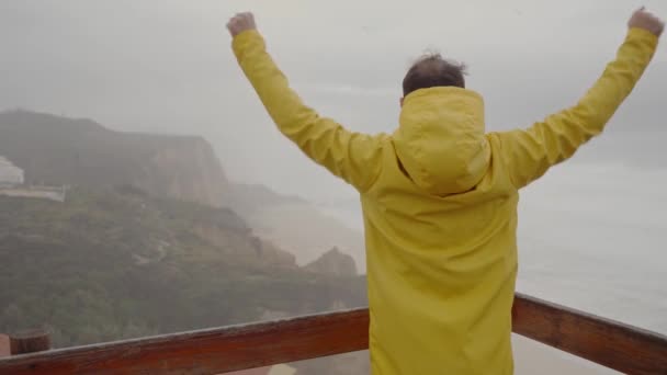 一个穿着黄色雨衣的人站在阳台上的视频 — 图库视频影像