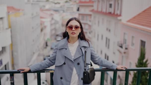 전망과 카메라를 발코니에 트렌치 코트와 선글라스에 매력적인 여성의 초상화 — 비디오