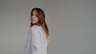 Beyaz gömlekli güzel bir kadın stüdyoda beyaz arka planda kameraya poz veriyor. Doğal makyajlı çekici genç bir kadının portresi. 