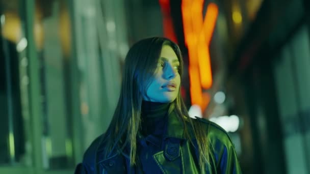 Deri Ceketli Çekici Bir Kadın Şehir Sokaklarında Neon Işıklarla Yürüyor — Stok video