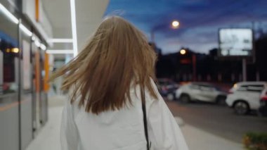 Neşeli mutlu kadın gece şehrinde sokakta yürüyor ve dönüyor. Güzel, güler yüzlü, neşeli bir kadın. 
