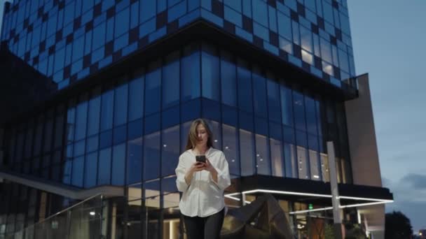 Bizneswoman Białej Koszuli Trzymać Smartfona Czytania Wiadomości Tekstowych Podczas Chodzenia — Wideo stockowe
