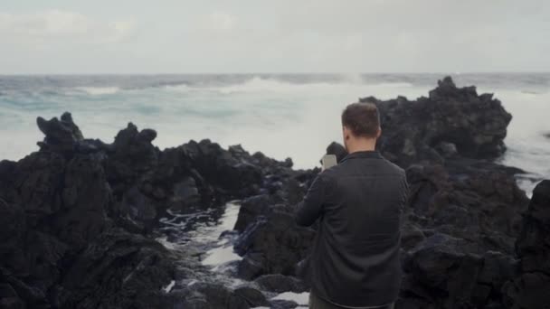 Yürürken Akıllı Telefon Kamerasıyla Deniz Dalgaları Çeken Adamın Arka Görüntüsü — Stok video