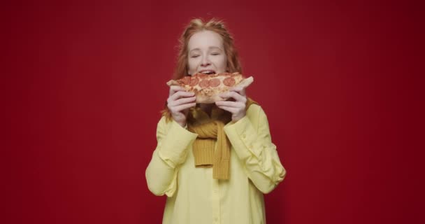 おいしいピザを食べて 赤い背景で食べ物を楽しんでいる若い女性 新鮮なイタリアのピザのハッピーな女性の咬傷スライス ファストフードコンセプト — ストック動画