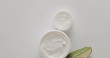 Doğal malzemelere dayalı kozmetik yağları, fırça, tonik, vücut bakımı, cilt bakımı. Kozmetik ve güzellik tedavisi için avokadolu kavanozlar, şişeler ve tüpler beyaz bir arka planda dönüyor..