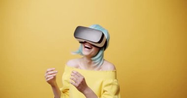 VR kulaklıklı, mavi saçlı, gülümseyen ve işaret eden genç bir kadının statik görüntüsü. Sonra sarı arka planda siber uzayı keşfederken başparmağını kaldırıyor. Sanal gerçekliği onaylayan kadın