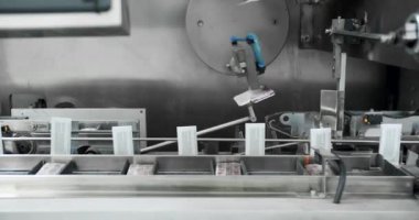 Tıbbi fabrikada üretim hattı. Robotik kol nakil bandına ilaç paketi koydu. Otomatik üretim hattında paketlenmiş mallar. Uyuşturucu ambalajı. İlaç imalatının üretim hattı