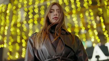 Deri ceketli şık, kendine güvenen bir kadın gece sokakta şehir ışıklarıyla yürüyor. Bokeh arka planında çekici bir kadın portresi