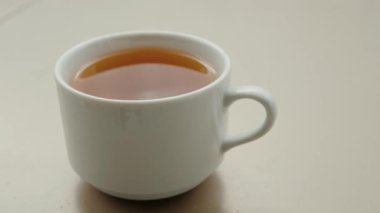 Beyaz seramik fincana yakın kafeterya masasında geleneksel Çin çayı. Kahvaltıda doğal bitkisel içeceklerle dolu bir bardak.