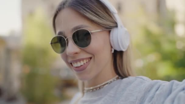 Kobieta Okularach Przeciwsłonecznych Słuchawkach Uśmiecha Się Podczas Robienia Selfie Pokazując — Wideo stockowe