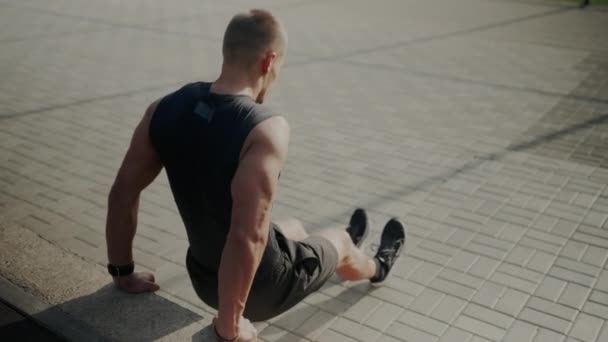 一个穿短裤的男人在硬木地板上做俯卧撑 双手放在地上 肘部弯曲 大腿和脚接触木头 — 图库视频影像
