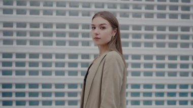 Bronz ceketli şık bir genç kadın, çeşitli şehir arkaplanlarına karşı poz veriyor, kameraya güvenle bakıyor. Yakın plan çekimler kusursuz cildini, uzun saçlarını ve moda tasarımını gözler önüne seriyor.