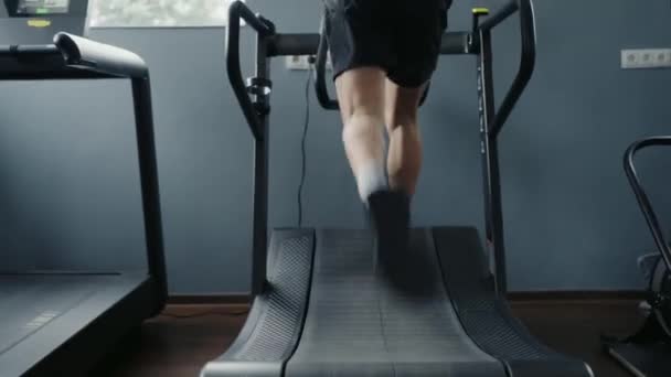 ジムでトレッドミルで走っている男性の足のクローズアップ 運動選手ランナーは フィットネスクラブで心臓トレーニングとトレーニングを持っています スポーツと健康的なライフスタイルのコンセプト — ストック動画