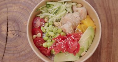 Geleneksel Hawaii çiğ balık salatası. Diyet öğle yemeğinde taze balık ve sebze. Japon yemeği, karides, pirinç, avokado, mango, edamame fasulyesi, ahşap arka planda salatalık..