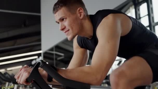 Bir Adam Spor Salonunda Egzersiz Bisikletine Biniyor Uyluk Kaslarını Çalıştırıyor — Stok video