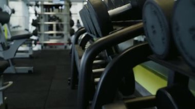 Spor yapmak ya da ağırlık çalışmak için farklı demir halterlere sahip fitness kulübünün içi. Modern spor salonundaki spor malzemeleriyle rafa yakın çekim..