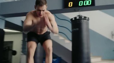 Spor salonunda kas egzersizi yapan genç bir sporcu. Sportif erkek fonksiyonel antrenman yapıyor ve kutunun üstüne atlıyor. Spor ve aktif yaşam tarzı kavramı