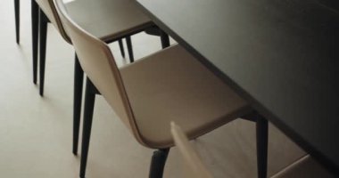Modern mutfaktaki ahşap yemek masasının yanındaki rahat boş sandalyeye yakın çekim. Modern mobilyaları olan şık bir dairenin içinde detaylar