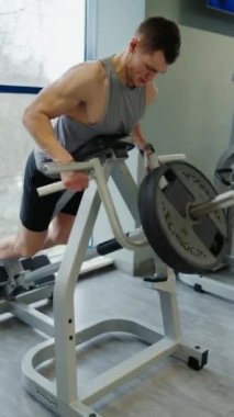 Atletik adam eğitim aparatlarıyla egzersiz yapıyor. Genç sporcu erkek spor aletlerini kullanarak spor yapıyor. Spor ve aktif yaşam tarzı konsepti. Dikey video