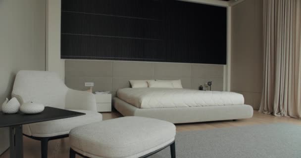 モダンなインテリア ダブルベッド 快適なアームチェア コーヒーテーブルが備わる広々としたベッドルーム ミニマリストスタイルのエレガントなベッドルームの現代的な家具 — ストック動画