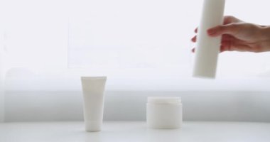 Masa kremini sürmüş, beyaz arka planda kavanozdan nemlendirici losyon sürmüş. Doğal kozmetik ürünleri, cilt bakım ürünleri. Cilt masajı için kozmetik ürünleri ve süngerlerle dolu şişeler..