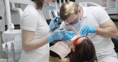 Diş hekimi, modern diş sağlığı kliniğinde hasta için diş temizliği yapıyor. Diş sağlığı kliniği. Ağız temizliği ve prezervatif temizliği. Diş temizliğinde kadın hasta. Diş temizliği prosedürü. Diş temizliği.