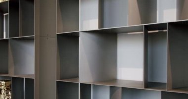 Oturma odasındaki duvarın yakınındaki boş kitaplığa yakın çekim. Modern mobilya, düzenleme alanı kitaplığı