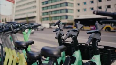 Araba trafiği olan yolun yakınındaki caddede kiralık bisiklet ve elektrikli scooterlara dikkat edin. Şehir merkezine yakın bir yerde bisiklet kiralamış. Çevre taşımacılığı kavramı